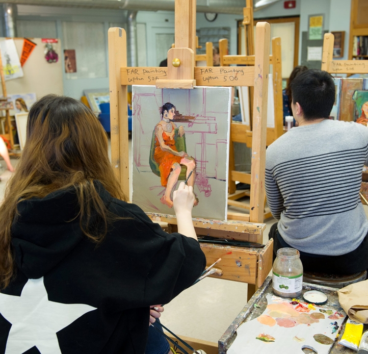Students painting a model in class