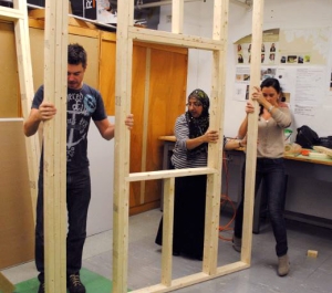People constructing a wall with 2x4s.